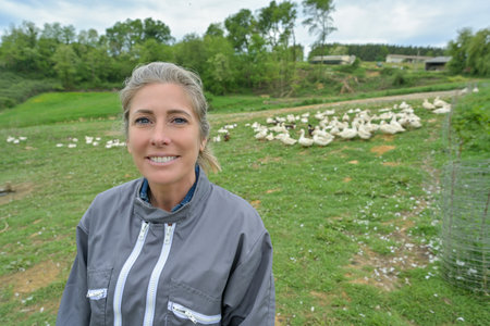 Portrait of a woman standing in the middle of her duck farm in a fieldの写真素材