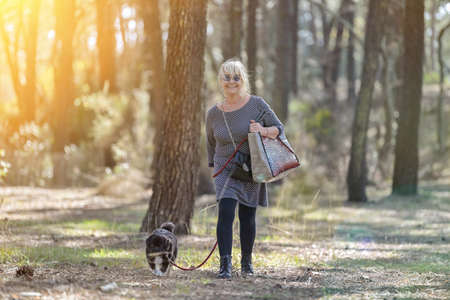 Lonely retired woman walking her dog in the woodsの写真素材