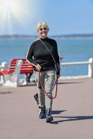 Lonely retired woman walking her dog along the coastの写真素材