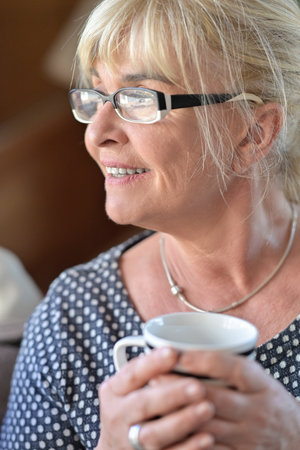 Portrait of a mature blonde retired woman drinking a cup of teaの写真素材