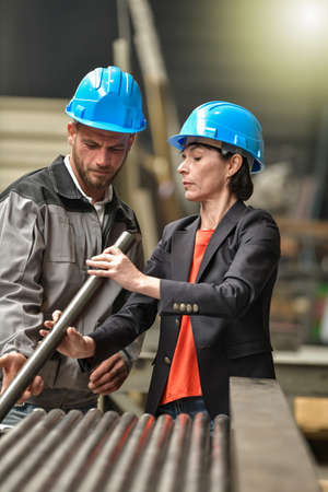 Confident female engineer is giving instruction and showing blueprint to a male worker
