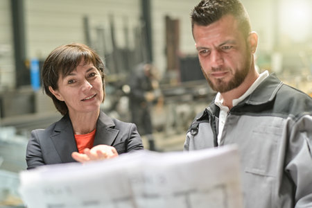 Confident businesswoman is showing a blueprint to a male worker