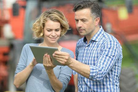 Couple of Farmer analyzes the harvesting in a field over a digital tabletの写真素材