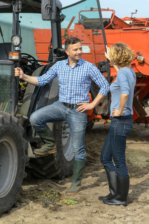 Farmer couple next to their tractor in the filedの写真素材