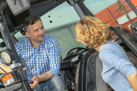 Farmer couple next to their tractor in the filedの写真素材