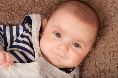 Baby boy reclining on brown blanket