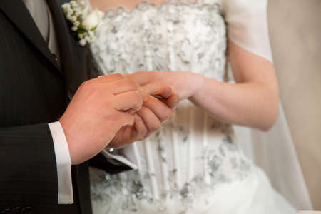 The groom puts  the  wedding ring to finger of the bride
