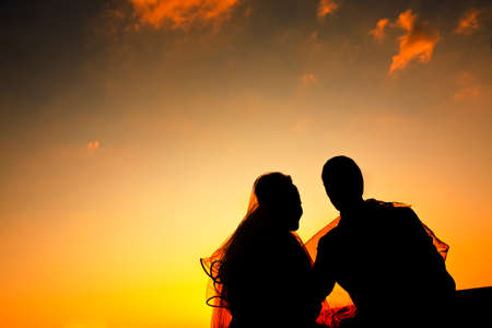silhouette of a young bride and groom on Sunset backgroundの写真素材