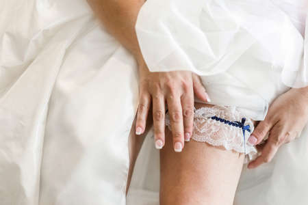 Bride putting garter on leg.の写真素材