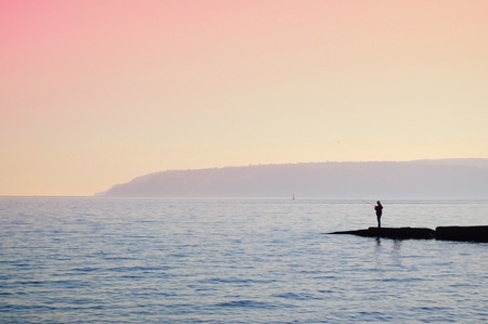 Silhouette of a fisherman at the sea at sunset