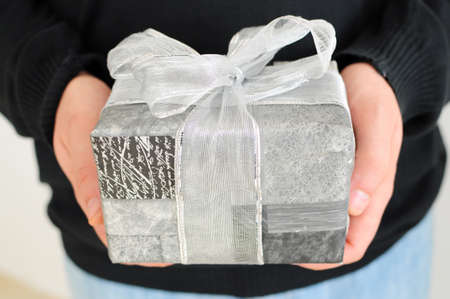 close up of man giving gift in silver wrapping の写真素材