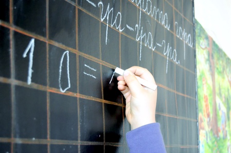 child hand writing numbers on school blackboard close upの写真素材