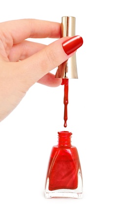 Woman holding brush over opened bottle of red nail polish の写真素材
