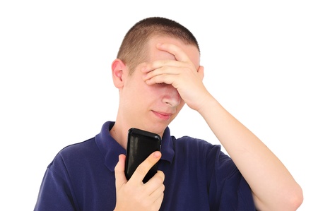 Young man with hand on face while holding phoneの写真素材