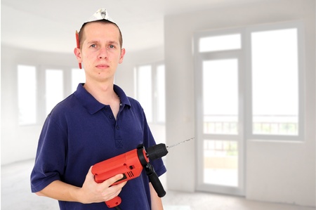 Young serious man with drill and paper hat isolated on whiteの写真素材