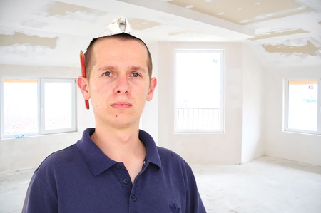 Young serious man with  paper hat in newly build unfinished roomの写真素材