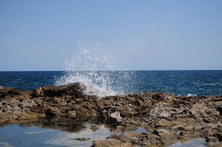 Waves splashing into rocks at seaの写真素材