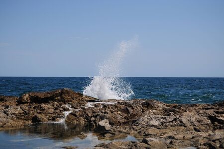 Waves splashing into rocks at seaの写真素材