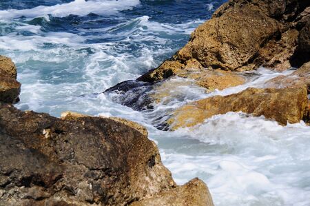 Waves splashing into rocks at seaの写真素材