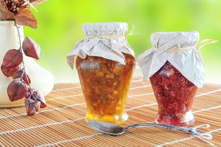 Two jars of fruit jam and a spoon on natural backgroundの写真素材
