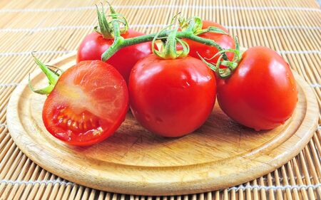 Branch of fresh tomatoes on wooden boardの写真素材