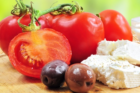 Closeup of fresh tomatoes, olives and white cheese on wooden boardの写真素材