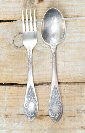 Vintage silver fork and spoon with ornaments on wooden backgroundの写真素材