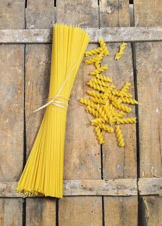 Spaghetti and fusilli on wooden backgroundの写真素材
