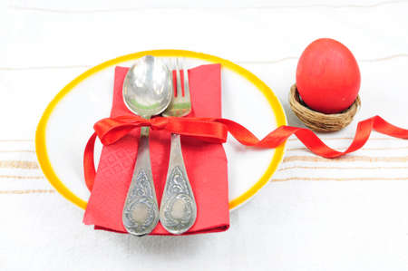 Easter dinner or lunch set - fork and spoon inplate with red colored eggの写真素材