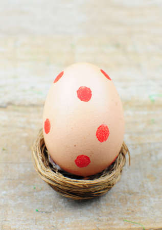 Easter egg with red dots in nest on wooden backgroundの写真素材