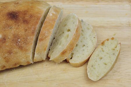 Homemade loaf of bread and slices on wooden boardの写真素材