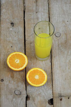 Fresh orange juice and two halves of a fruit on wooden tableの写真素材