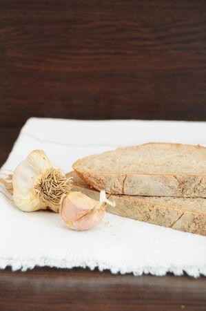 Slices of bread and garlic on white clothの写真素材