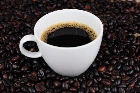 Coffee cup over scattered coffee beansの写真素材