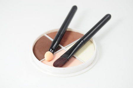 Set of four eyeshadows and makeup brushes on white background