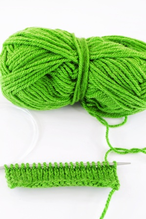 Green and yarn and needles and piece of knittingの写真素材