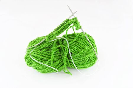Green and yarn and needles and piece of knittingの写真素材