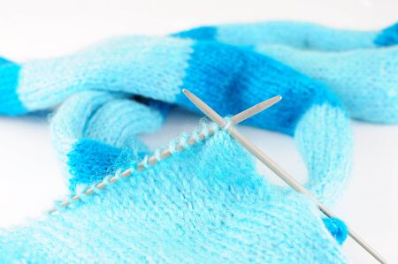 Needles knitting blue scarf on white backgroundの写真素材