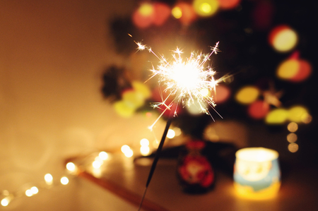 Sparkle stick  with lights and christmas tree on the backgroundの写真素材