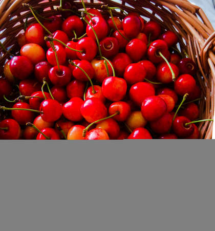 Fresh ripe cherries in a wicker basket on a wooden background