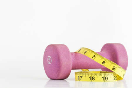 A dumbell is wrapped with a measuring tape to show benefits of weigh lifting on health and weight lossの写真素材