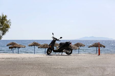 panorama view of the beach sea black motorcycle moped stands on the roadの写真素材