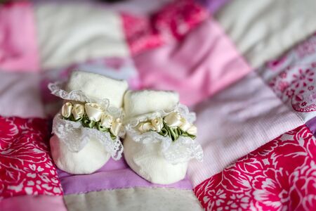 close up baby booties white flowers roses for a little girl on a pink plaid backgroundの写真素材