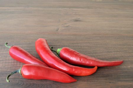 Red pepper. On wooden surfaces are four pods of red hot pepper.の写真素材