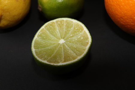 Grapefruit, orange, lemon and lime isolated on a black background. Citrus fruits in the section. Citrus slices. Still life of fruit.の写真素材