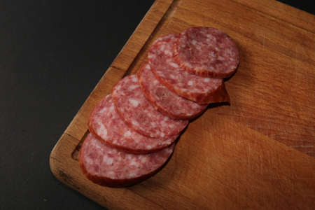 Salami sausage cut into slices on a stick isolated on a black backgroundの写真素材