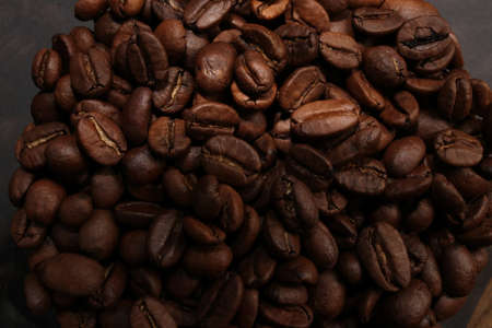 Black coffee beans in large quantities, close-up, isolated on a black background