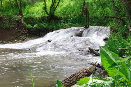 A small waterfall in the forest. Bright juicy greens and splashes of water. A quiet and peaceful place for family holidaysの写真素材
