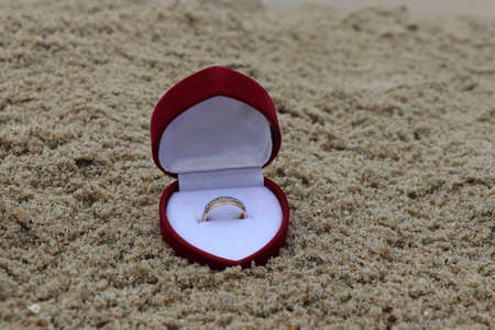 A ring in a box on a sandy beach. A romantic way to propose. An engagement ring. Engagement ring