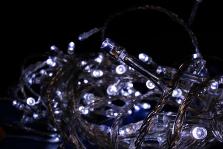 Small white light bulbs isolated on a black background. New Year's garland. Christmas Decorationの写真素材
